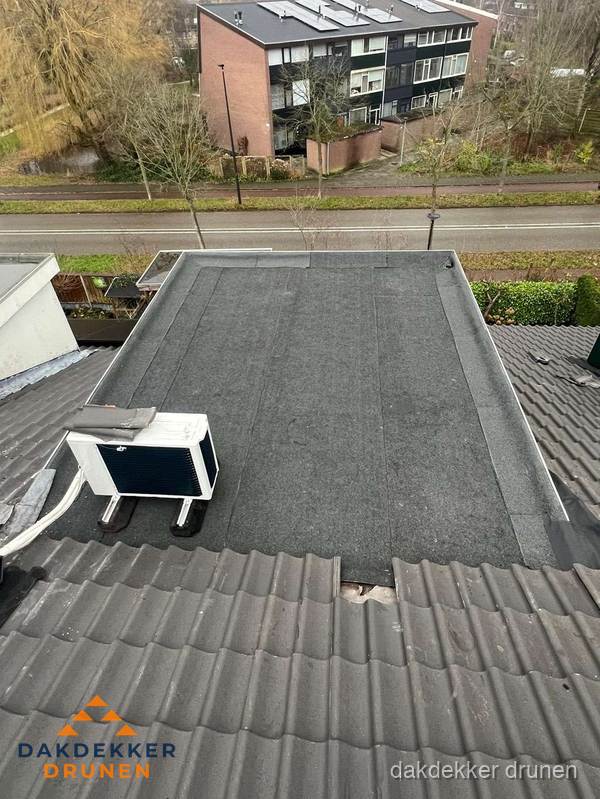 Plat dak inspectie met bitumen bedekking naast schuin pannendak in Drunen