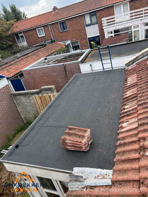 Plat dak aanbouw met bitumen naast schuin pannendak in Drunen