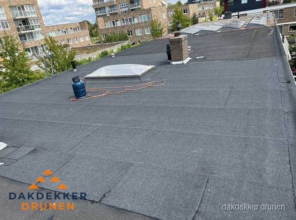 Bitumen dakbedekking op plat dak met lichtkoepel en schoorsteen in Drunen
