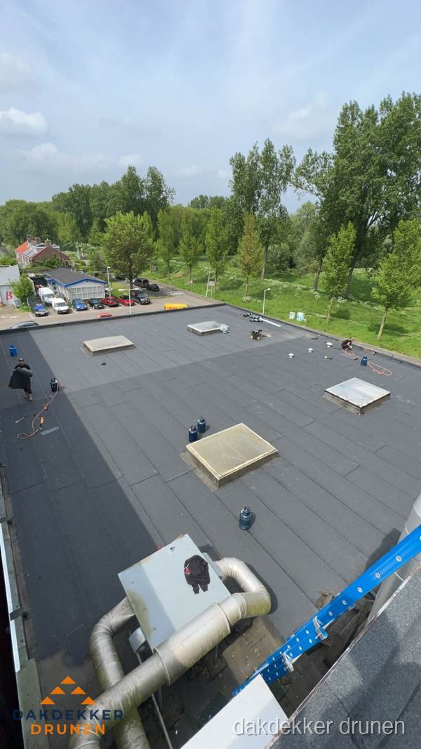 Dakdekker aan het werk op groot plat dak met bitumen in Drunen
